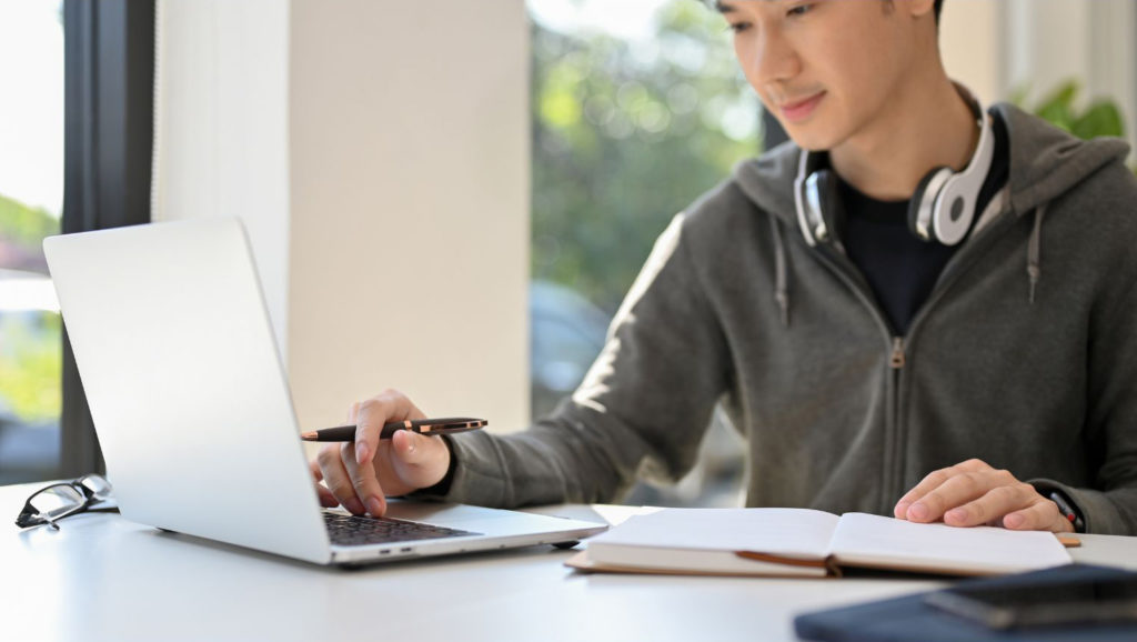 ノートパソコンで勉強している男子大学生