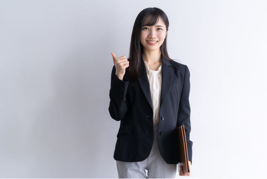 黒いジャケットを着た右手親指を差し出して笑顔の女性