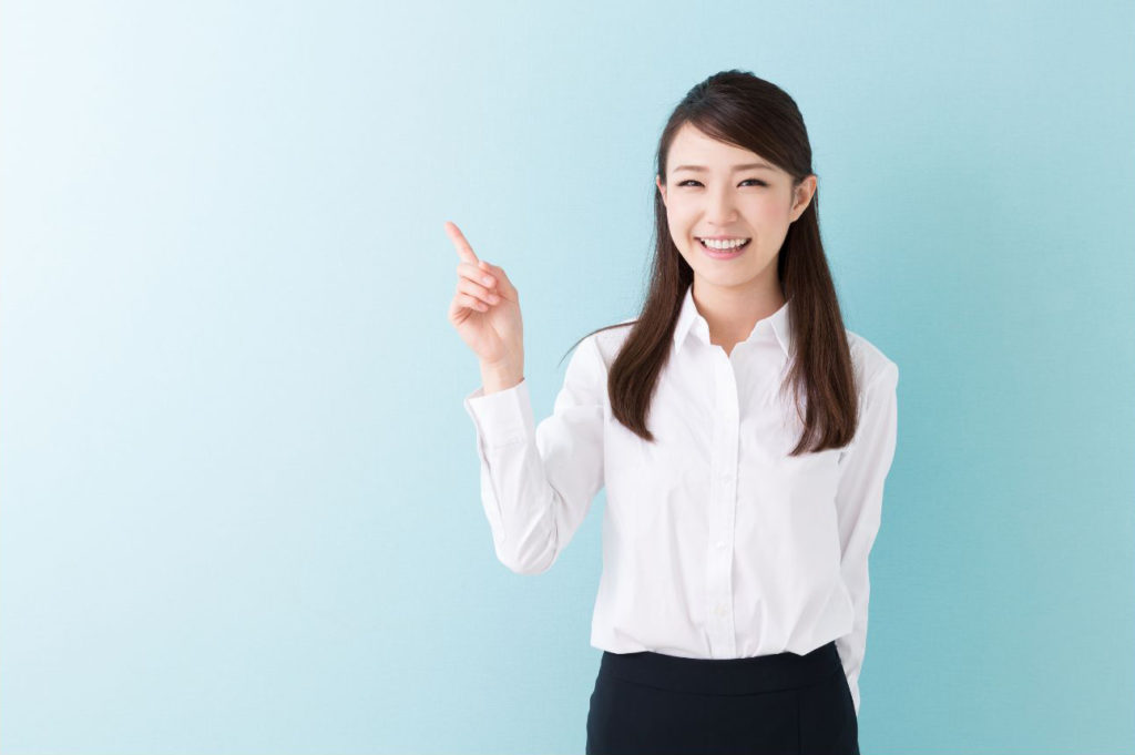 おすすめの右人差し指を上向きにさしている笑顔の若い女性