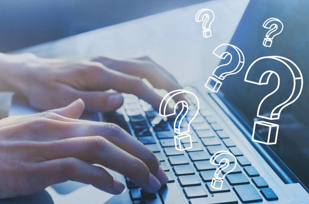 ラップトップを打っている指とクエスチョンマーク