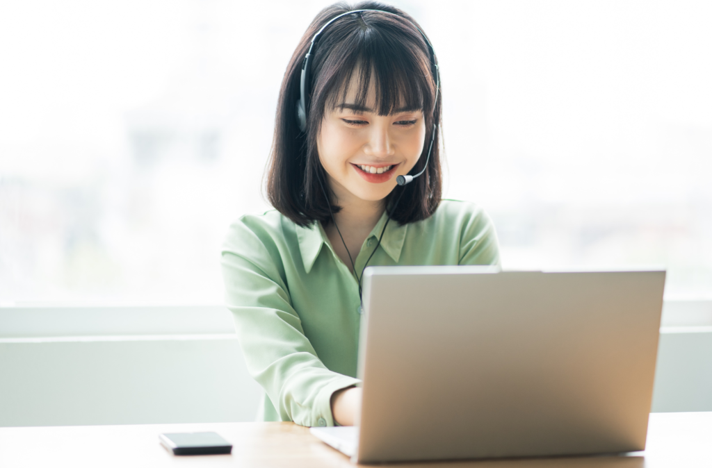 ヘッドフォンをして笑顔でノートパソコンをいじっている若い女性